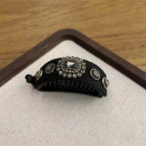 Detailed macro view of black banana hair clip with grey gemstone and crystal accents