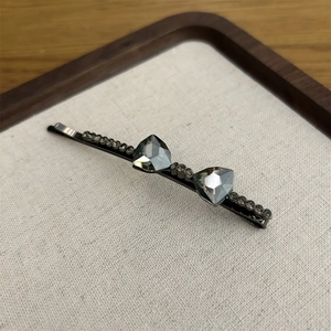 Macro detail of charcoal grey crystal bow hair clip with fine rhinestone inlay