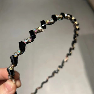 Détail de serre-tête ondulé noir orné de perles et strass en cristal scintillants