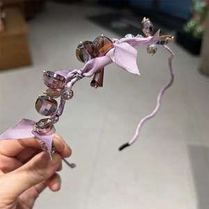 Detailed view of purple satin headband with sparkling crystal beads and ribbon bow