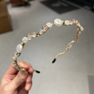Close-up of golden headband with elegant white pearls and peach crystal beads