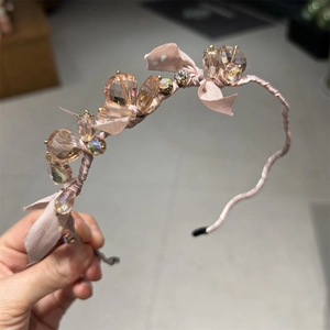 Detailed shot of pink silk headband decorated with light pink crystals and a delicate bow