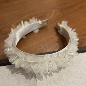 Nahaufnahme der Organza-Blütenblätter und Kristallperlen auf dem Satin-Haarreif