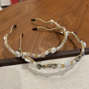Detail of thin headbands with crystals and pearls on a wooden and beige surface