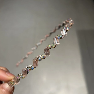 Détail d'un serre-tête ondulé avec cristaux roses et strass colorés sur tissu argenté
