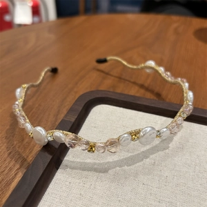 Detail of a wavy gold headband with elegant white pearls and pink crystals