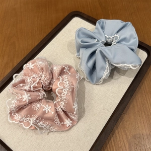 Détails de chouchous avec broderie florale et dentelle bleue sur un plateau chic