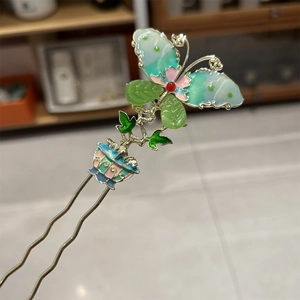 Detailed macro of golden butterfly hairpin with blue green gradient wings and leaves