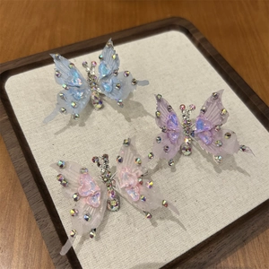 Dettaglio di tre fermagli per capelli a farfalla 3D con strass lucidi e nastri in rete morbidi