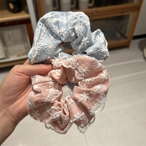 Gros plan sur les chouchous en satin bleu et rose avec broderie florale en dentelle blanche
