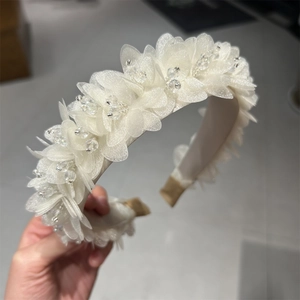 Detail eines weißen Organza Blumen Haarreifens mit Schichten und Perlenverzierungen