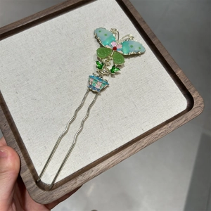 Detail view of U-shaped hair pin featuring gold butterfly and colorful enamel floral accents