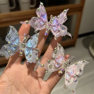 Tre eleganti fermagli per capelli a farfalla con gemme e ali di tulle in colori tenui