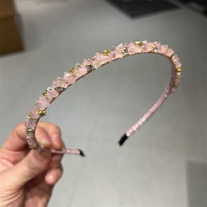 Détail d'un serre-tête en cristal rose avec strass brillants sur base en tissu