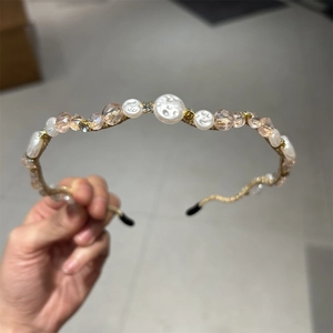 Detail view of gold metal headband with white pearls and pink crystal beads