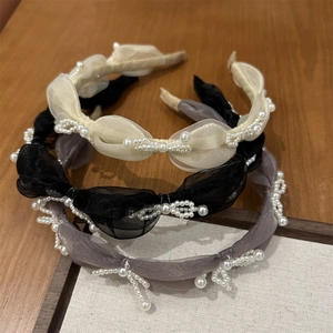 Close-up of three organza bow headbands with pearl accents in beige, black and grey colors