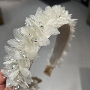 Detailansicht eines weißen Satin-Haarreifs mit handgemachten Stoffblumen und Kristallperlen