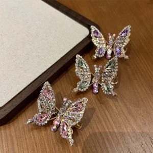 Dettaglio di tre fermagli per capelli a farfalla scintillanti in rosa, verde e viola