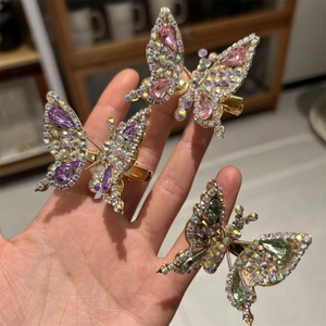 Dettaglio di tre fermagli a farfalla con strass colorati e base in lega dorata