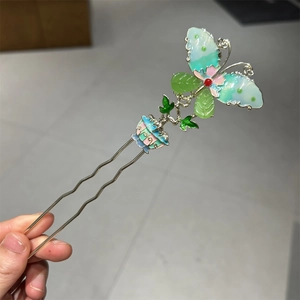 Detail of a U-shaped hairpin with a colorful enamel butterfly and floral accents