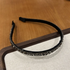 Close-up of elegant black headband with dense rows of sparkling grey rhinestones