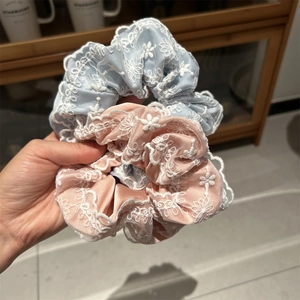 Vue détaillée des chouchous en dentelle bleu clair et rose avec broderie florale