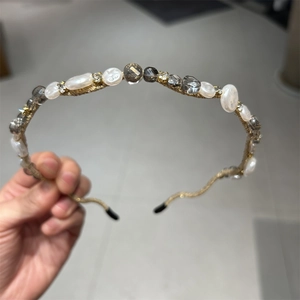 Detail showing wavy gold metal headband with pearls and sparkling faceted crystals