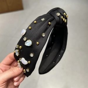 Texture détaillée du serre-tête en tissu noir avec perles dorées et strass brillants