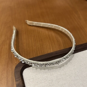 Detail of elegant satin headband with three rows of sparkling rhinestones on wood tray