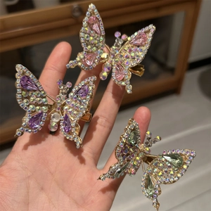 Dettaglio ravvicinato di fermagli per capelli a farfalla 3D mobili con strass colorati e oro