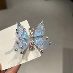 Dettaglio di un fermaglio per capelli a farfalla in rete blu con strass e gemma a cuore