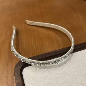 Close-up of elegant slim headband with sparkling round rhinestones and champagne fabric base
