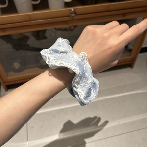 Détail du chouchou bleu clair avec broderie de dentelle porté au poignet