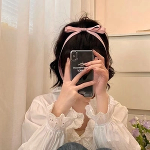 Pink satin bow headband with long ribbons shown worn in hair for a sweet aesthetic look