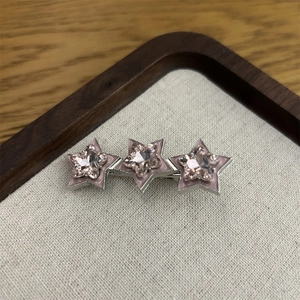 Detail von rosa sternförmigen Haarklammern mit Kristallen auf einem Stofftablett