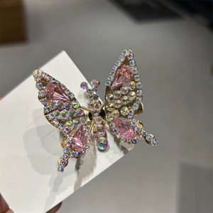 Dettaglio del fermaglio a farfalla dorata con cristalli rosa a goccia e strass colorati