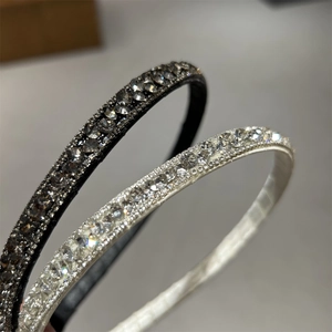 Close-up of thin black and white headbands with densely pavé-set shimmering crystals