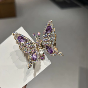 Dettaglio macro del fermaglio a farfalla dorato con cristalli viola e strass luccicanti