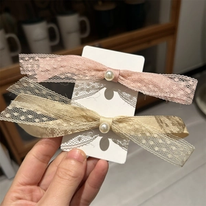 Détail des barrettes à cheveux en dentelle et perles, nœuds rose et champagne doré