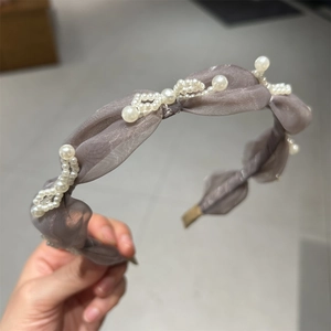 Detailed texture of grey-purple pleated chiffon headband decorated with white wavy pearls