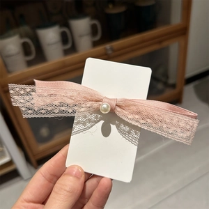 Barrette à cheveux élégante en dentelle rose avec perle sur une carte de présentation