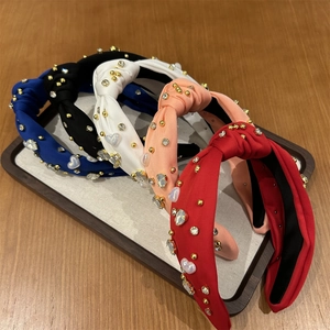 Détail de cinq serre-têtes en tissu noué avec perles dorées et accents de cœur en plateau