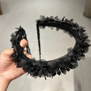 Detail von handgefertigten schwarzen Organza-Blüten und Perlen auf einem breiten Haarband