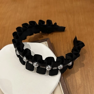 Détail d'un serre-tête en satin plissé noir orné de perles et de cristaux élégants