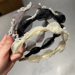 Detail of three tulle headbands with white pearl wavy patterns in black, grey and beige