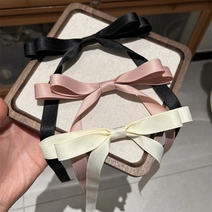 Detail of satin bow hair clips in black, pink and cream on a wooden display tray