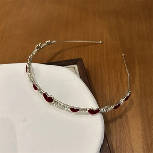Detail mit roten Samtherzen und glitzernden Strasssteinen auf einem schmalen silbernen Stirnband