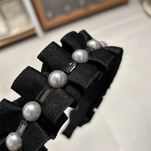 Gros plan du serre-tête plissé en satin noir avec perles blanches et cristaux