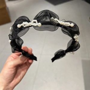 Detail of black organza headband featuring elegant clustered white pearls and pleated mesh
