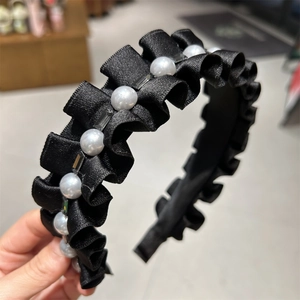 Détail d'un serre-tête en satin noir plissé avec perles blanches et cristaux